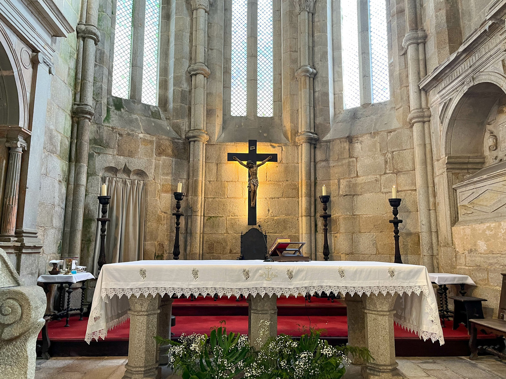 Stone altar and presbytery and stained glass windows in medieval Gothic style with candles and wooden cross in the Fortified Church of Leça do Balio. Porto, Portugal. 2023-01-15