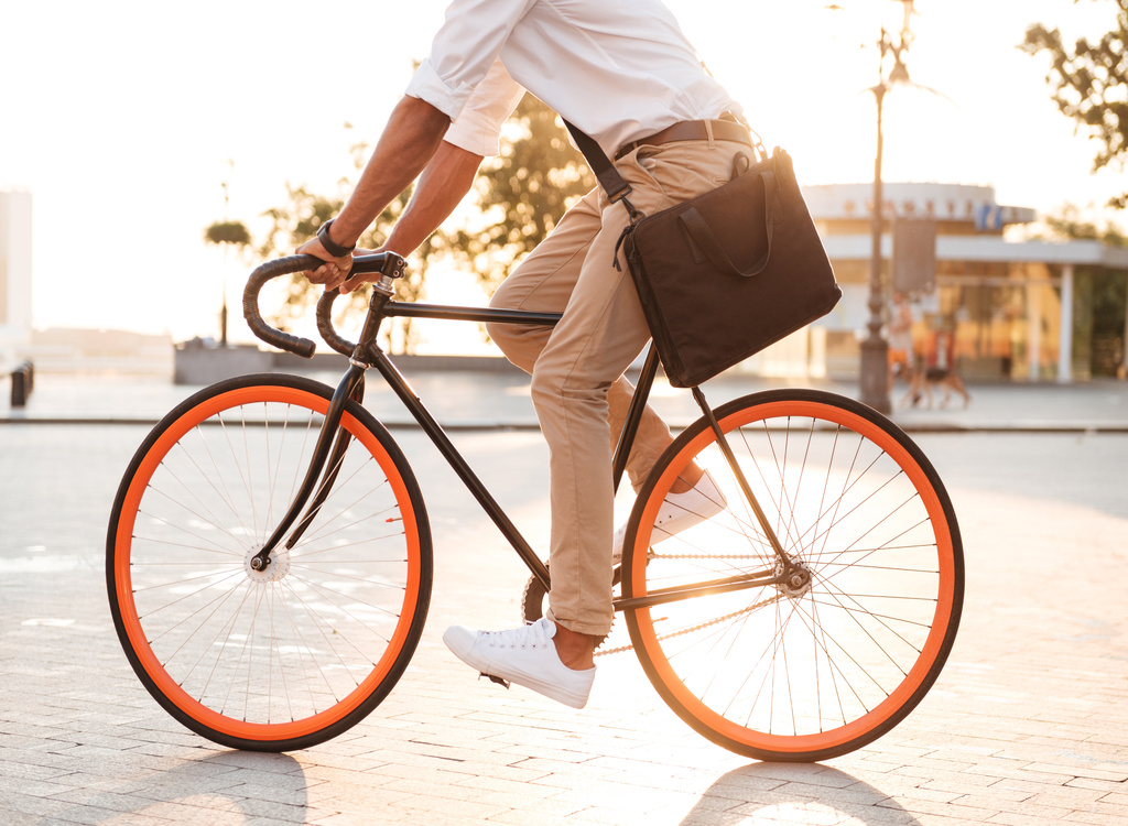 Cropped picture of handsome young african man early morning with bicycle walking outdoors.